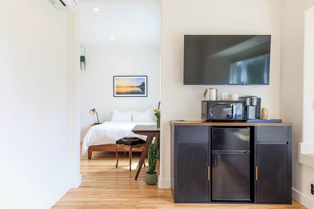A compact bedroom with a bed, bedside table, and a mounted TV.