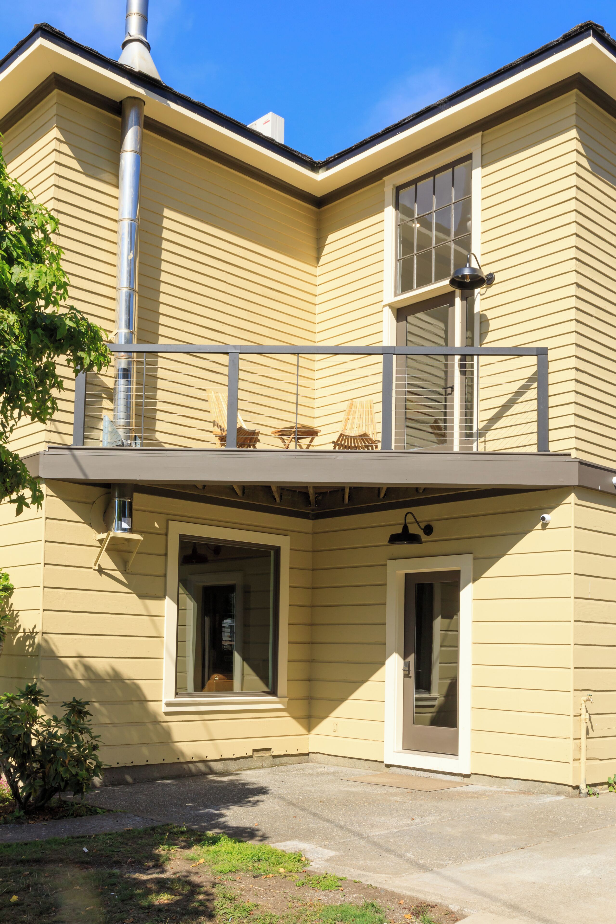 Un bâtiment à deux étages doté d’un balcon, d’une cheminée et d’une porte donnant sur l’intérieur.