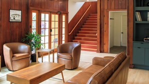 A spacious living area with a wooden staircase, leather sofas, and a wooden coffee table. - The Historic Schoolhouse Inn   (Trinidad)