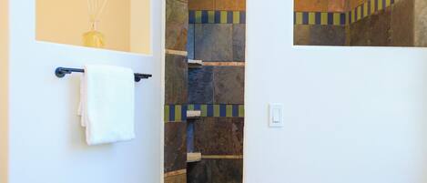 A bathroom with a white sink, a towel rack, and a wooden stool with rolled towels.