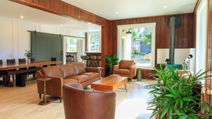 A spacious living area with a large wooden dining table, leather sofas, and a coffee table. - The Historic Schoolhouse Inn   (Trinidad)