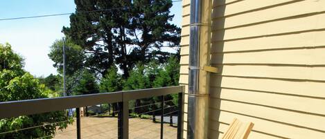 A wooden deck with two lounge chairs, a metal railing, and a view of a tree and grass.