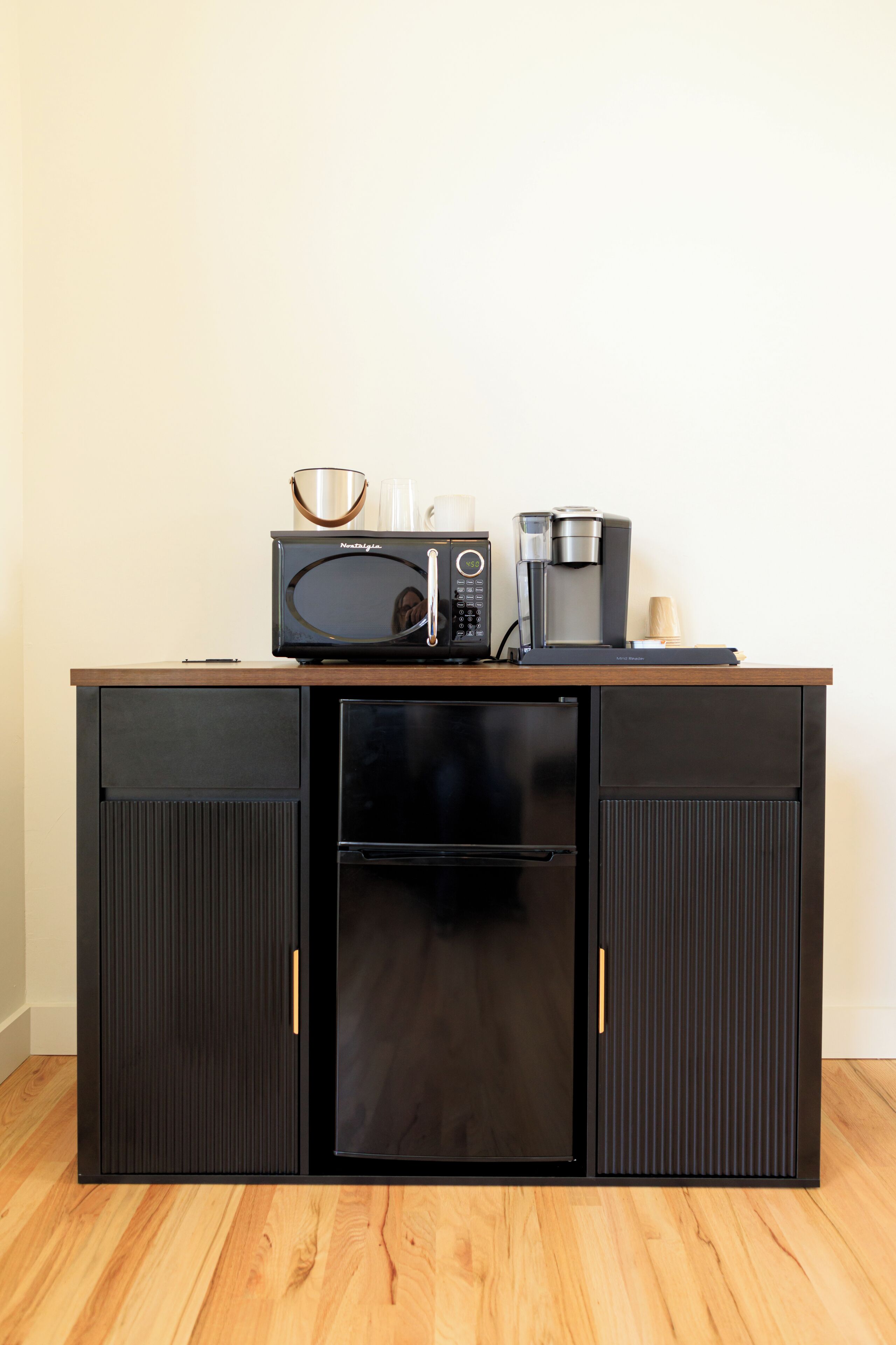 A compact kitchenette with a microwave, coffee maker, and refrigerator.