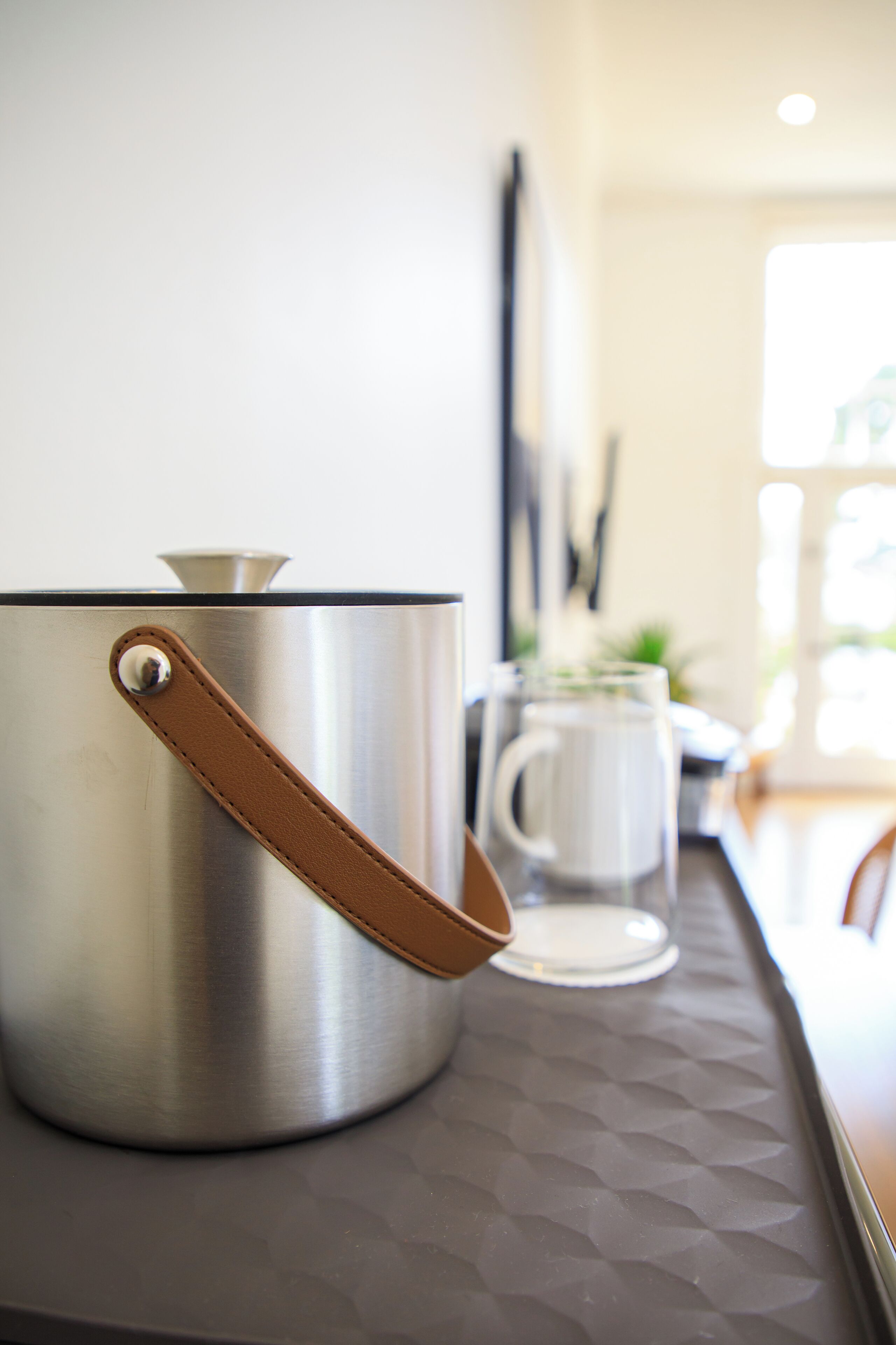 Una olla de acero inoxidable con un asa marrón sobre una encimera de cocina.