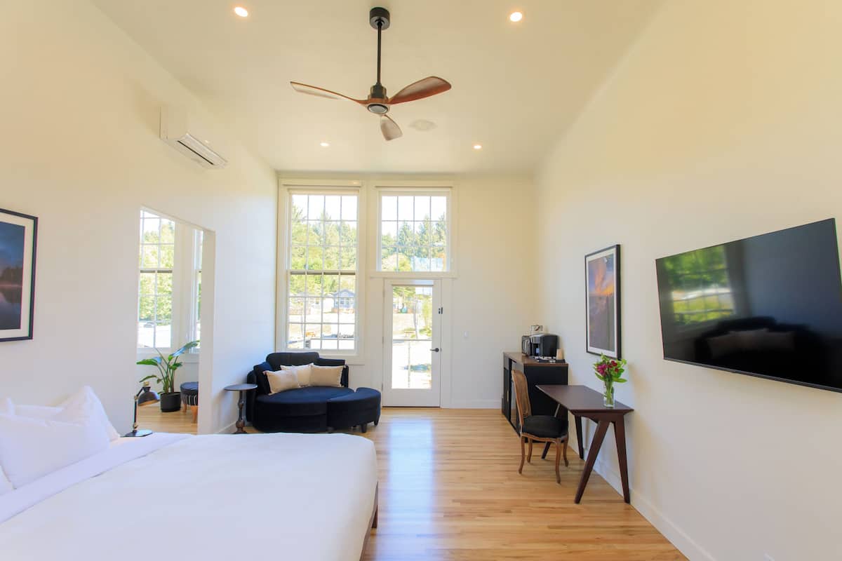 A spacious bedroom with a large bed, a ceiling fan, and a view through the door.