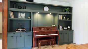Um quarto com um piano de cauda, uma estante de livros e um relógio na parede.