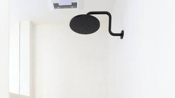 A minimalist shower area with a black showerhead and a hexagonal tile floor.