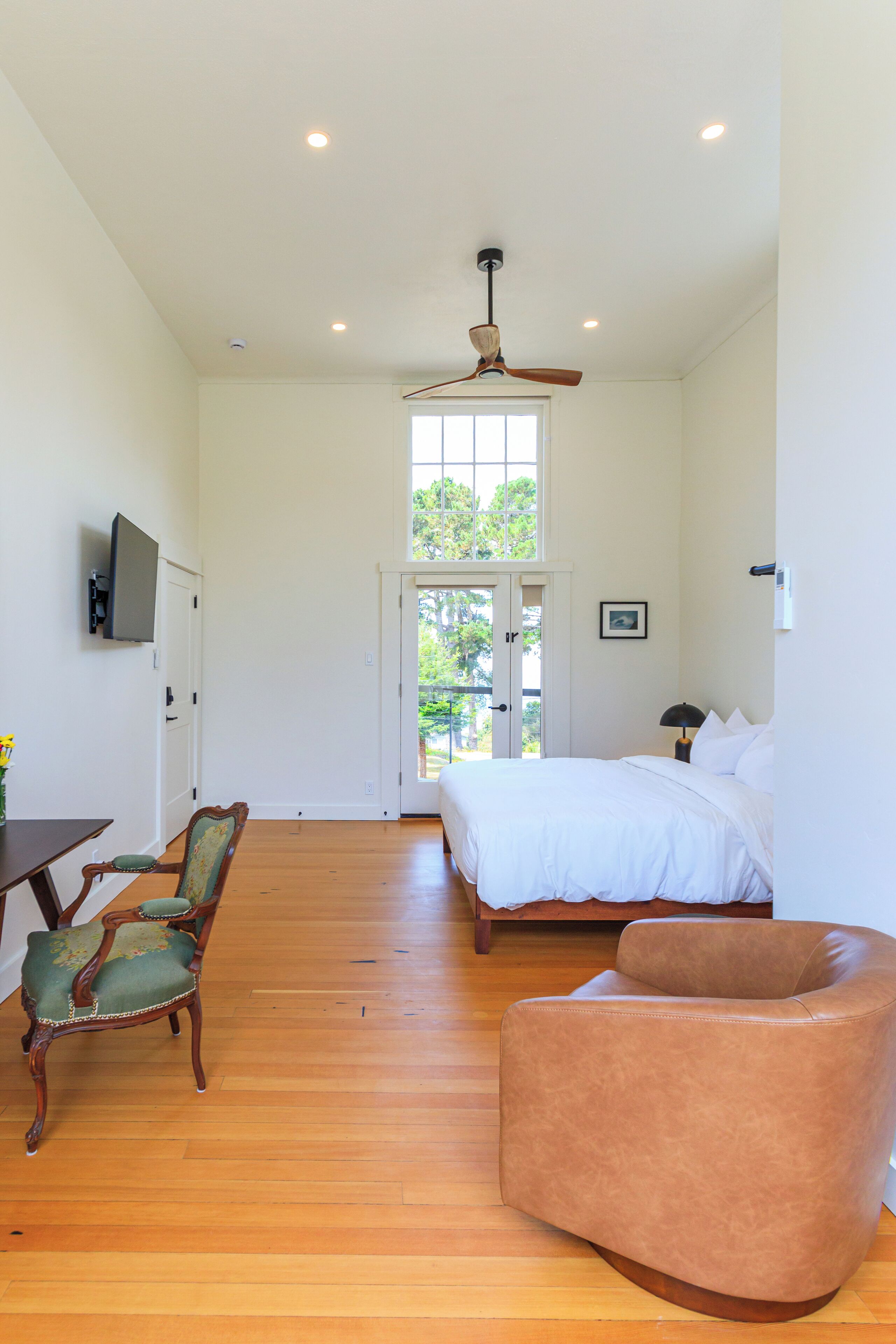 A bedroom with a bed, a chair, a desk, and a television.