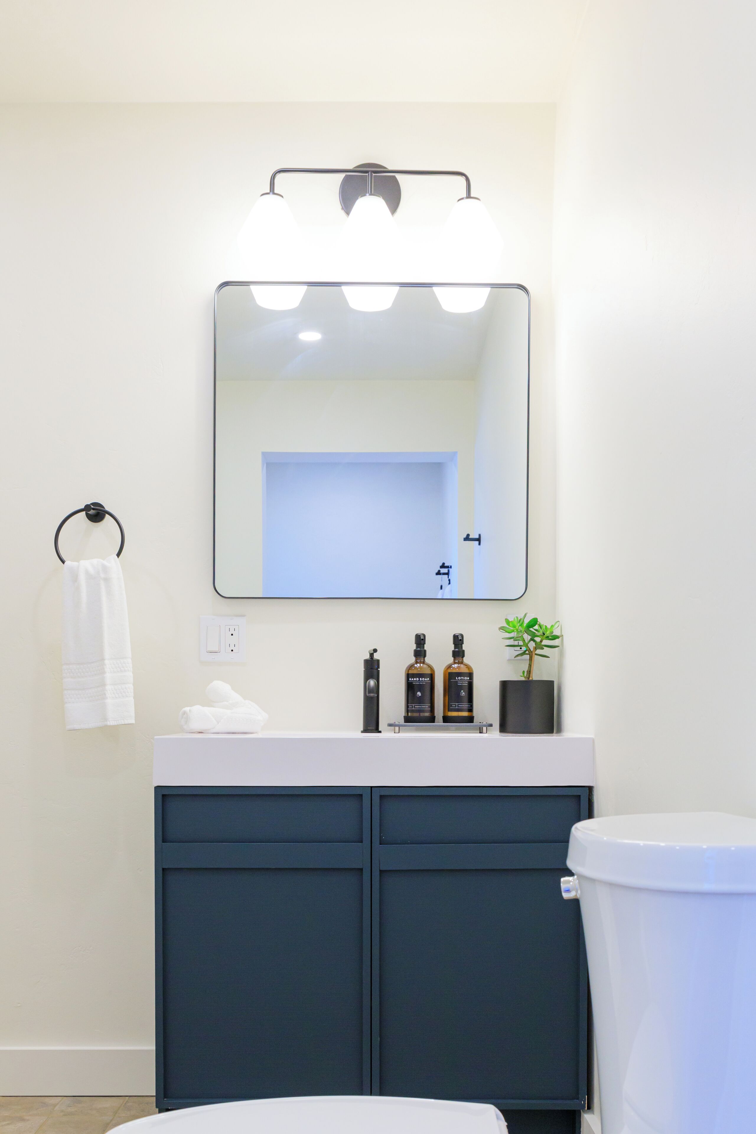 Ein Badezimmer mit Spiegel, Waschbecken, Handtuchhalter und Toilette.