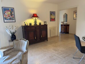 A room with a wooden cabinet, a red lamp, a framed picture, and a vase with white flowers. - Marilyn Beach - Sea view, terrace & private garage (Cannes)