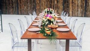 A long wooden table set with clear chairs, centerpieces, and glassware. - Suite 4 Hotel VOS - Superior Suite, Ocean View (Manuel Antonio)