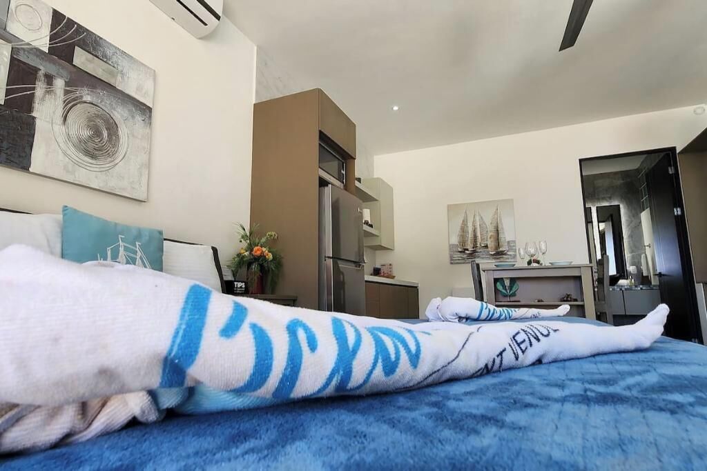 A hotel room with a bed, a refrigerator, a sink, and a mirror.