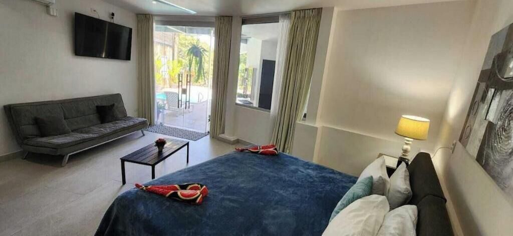 Une chambre d’hôtel équipée d’un lit, d’un canapé, d’une télévision, d’une lampe et offrant une vue sur l’extérieur.