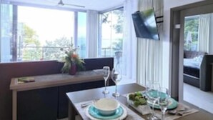 Un espace repas moderne avec une table dressée pour deux personnes, un banc et une vue sur l’extérieur.