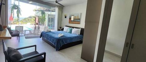 A hotel room with a bed, a desk, a chair, and a view of the outdoors.