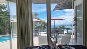 Habitación con un amplio ventanal con vistas a una piscina y zona de estar al aire libre.