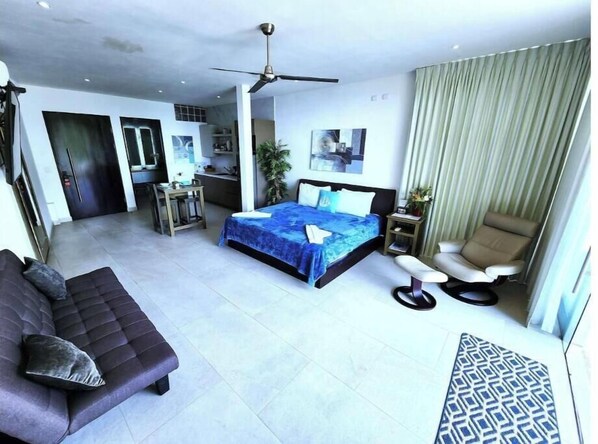 Une chambre d’hôtel moderne équipée d’un grand lit, d’un canapé, d’un bureau, d’une chaise et d’un ventilateur de plafond.