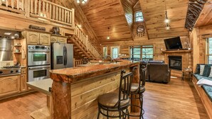 A log cabin interior with a kitchen, dining area, and living room.