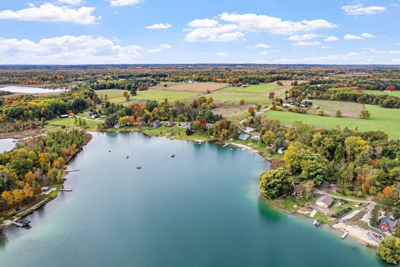 An aerial view of a lakeside property with boats, houses, and surrounding greenery.