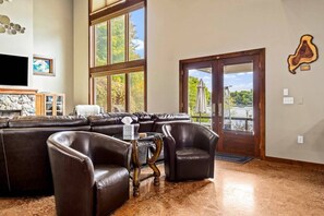 A living room with a sectional sofa, leather armchairs, a flat-screen TV, and a stone fireplace.