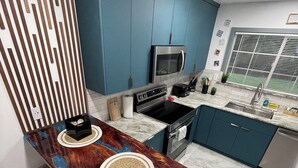 Une cuisine moderne avec des armoires bleues, un four à micro-ondes en acier inoxydable et un plan de travail en marbre.