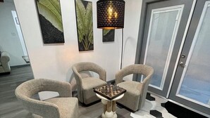 Un salon moderne avec des fauteuils à revêtement gris, une table basse centrale et un tapis à motifs hexagonaux originaux.