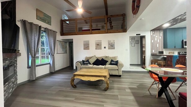Un vaste espace de vie doté d’un haut plafond, d’une table basse en bois, d’un canapé agrémenté de coussins décoratifs et d’une table à manger avec des chaises.