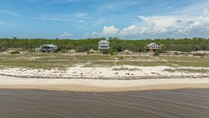 A coastal property with three houses, a sandy beach, and a forested background.