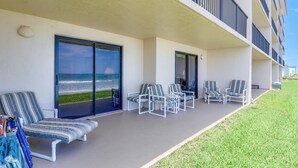 Ein Balkon mit Blick aufs Meer, weiße Stühle und ein blau gestreiftes Sofa.