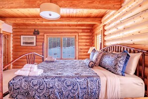 Un dormitorio tipo cabaña de madera con una cama, almohadas y una ventana.