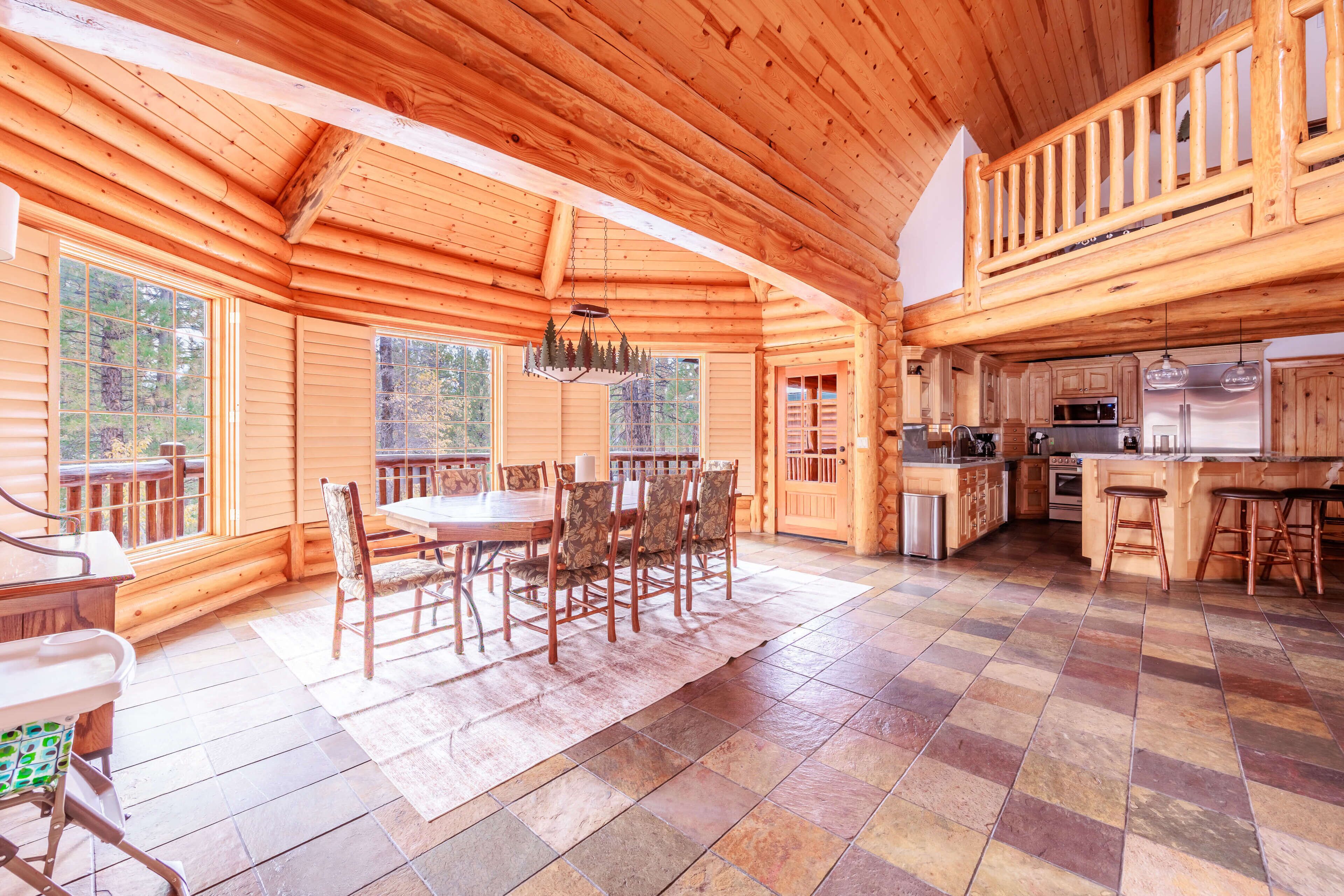Ein geräumiges Blockhaus-Interieur mit Essbereich, Küche und großen Fenstern.