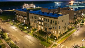 A multi-story building with a flat roof, a parking lot, and a waterfront view.