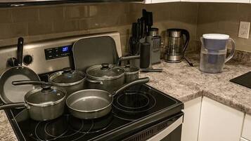 A kitchen with a microwave, stove, pots, and a coffee maker.