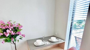 Ein kleiner Essbereich mit einem für zwei Personen gedeckten Tisch, einem rosa Stuhl und einem Blumentopf.
