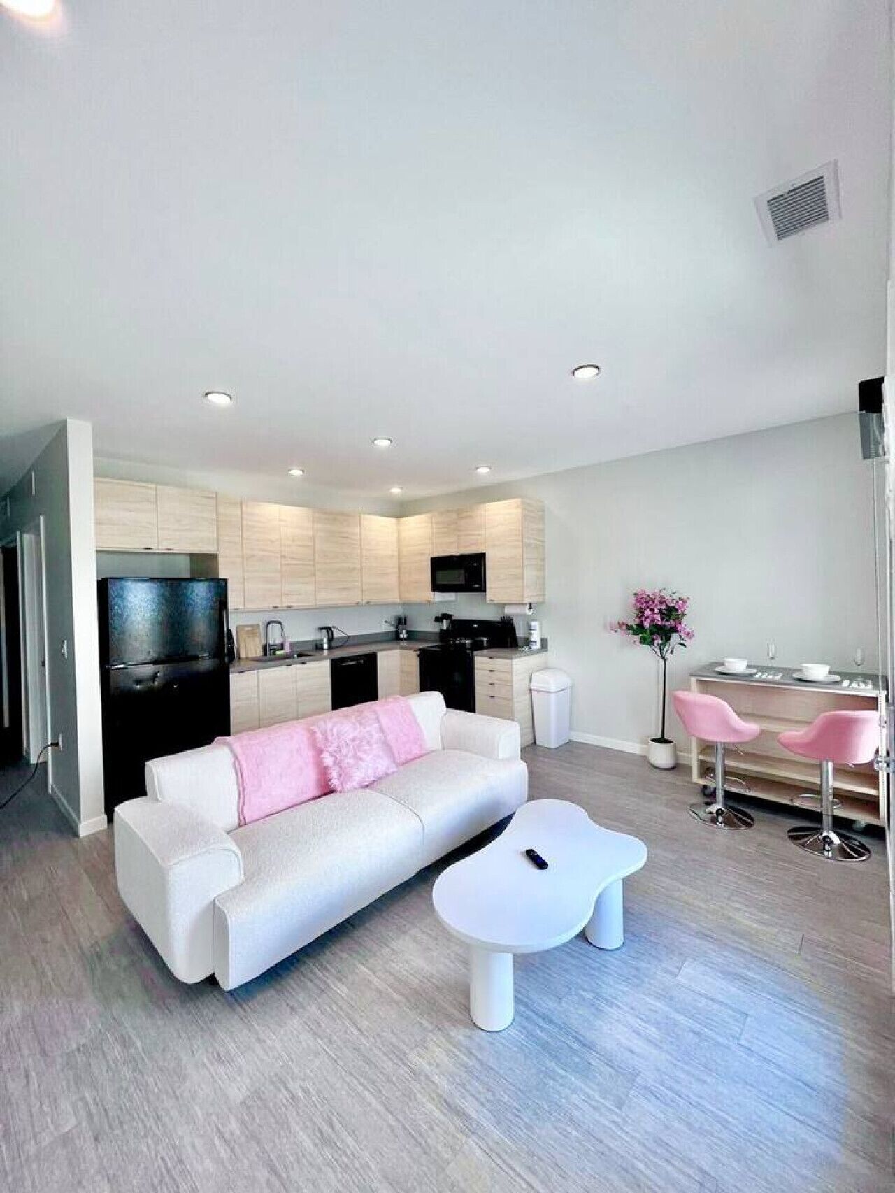 A modern living room with a white sofa, a coffee table, and a kitchen area with cabinets and appliances.