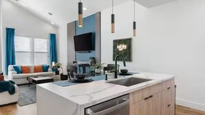 Une cuisine moderne dotée d’un îlot central, d’un lave-vaisselle intégré et de luminaires suspendus.