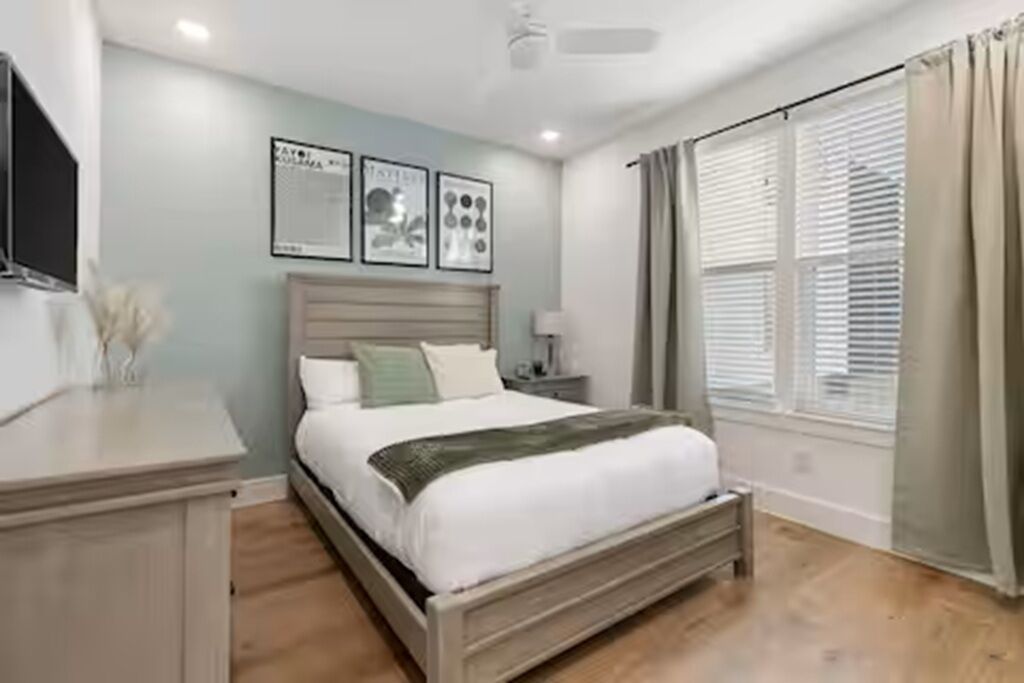 Une chambre à coucher avec un lit, une table de chevet et une fenêtre avec des rideaux.