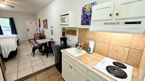 A compact hotel room with a kitchenette, a dining area, and a bed. - Wasser Lodge #206 | Sleeps 4 | Comal Riverfront (New Braunfels)