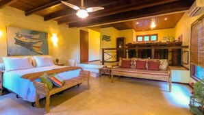 Una habitación con cama, sofá, mesa de comedor y ventilador de techo.