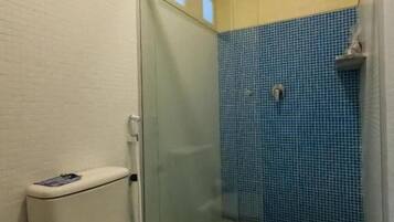 A bathroom with a toilet, a glass-enclosed shower with blue tiles, and a wooden ceiling.