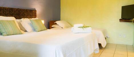 A hotel room with two beds, a television, and a wall-mounted air conditioner.