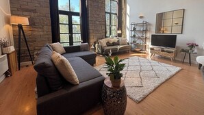 A modern living room with a sectional sofa, a TV, and a large window.