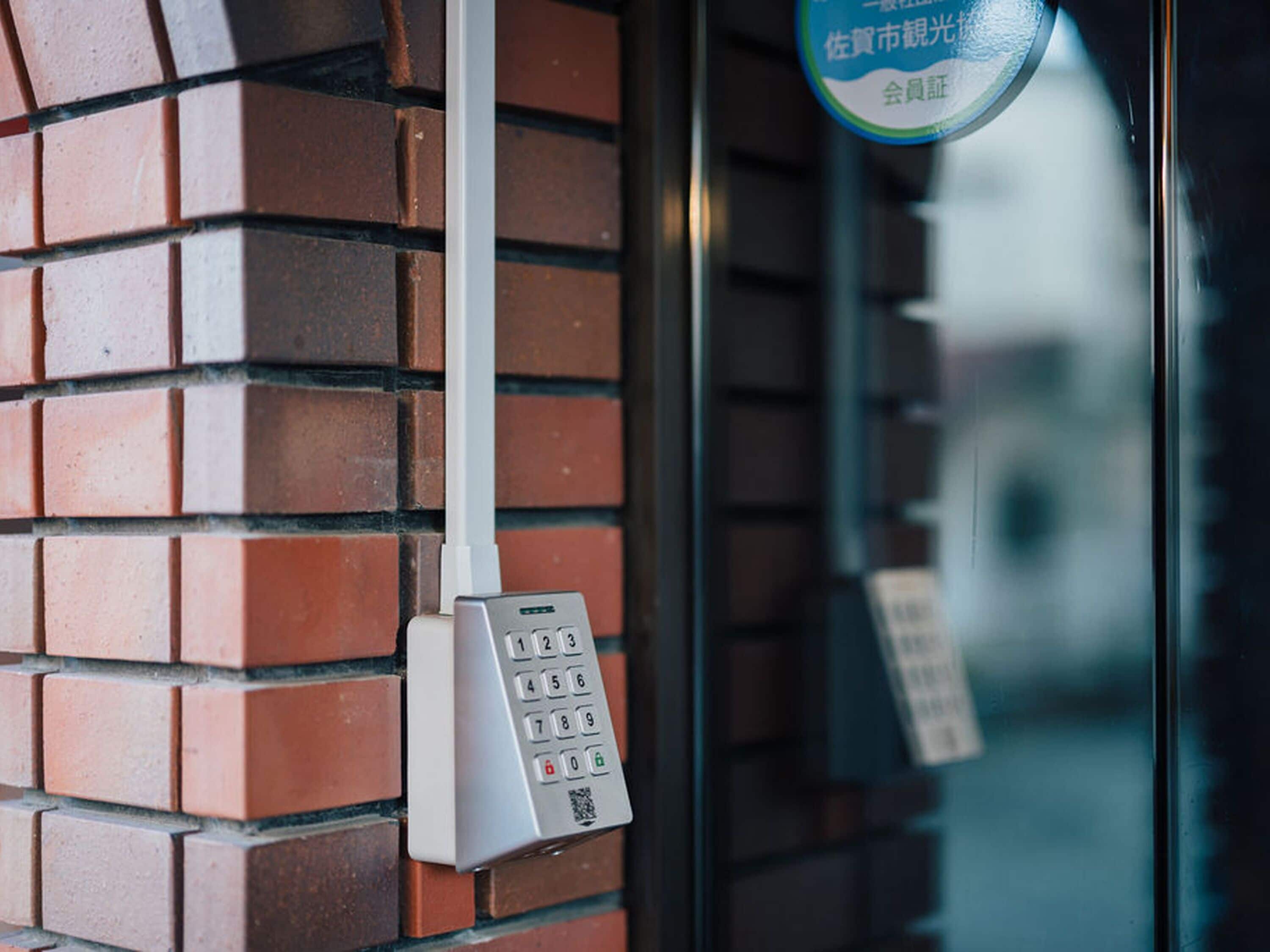 A keypad mounted on a brick wall, likely for a door or gate.