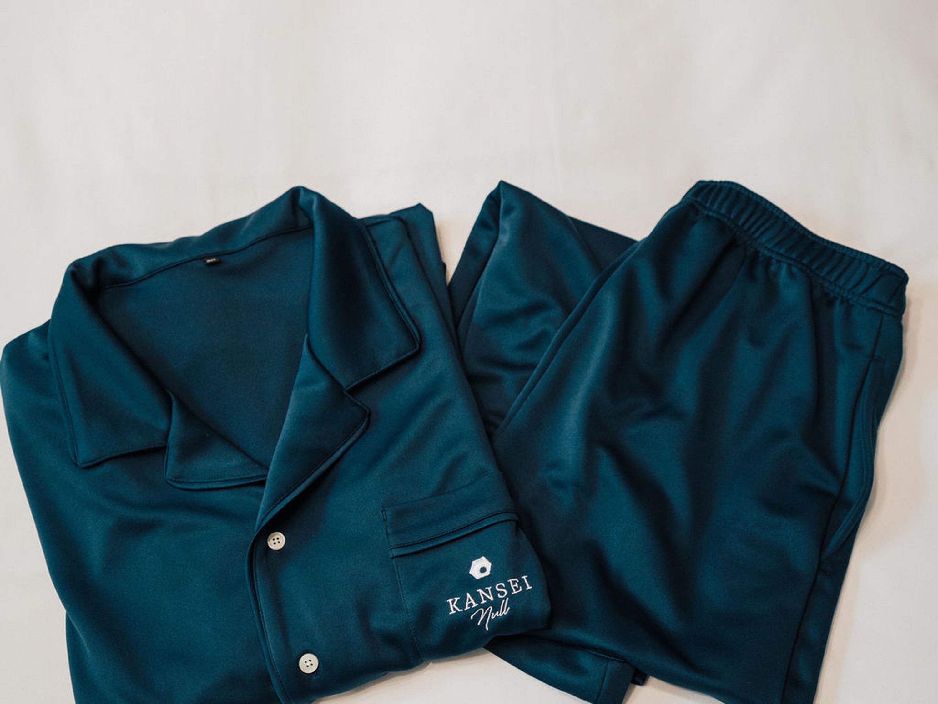 A pair of teal shorts with a pocket and a button detail.