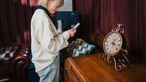 Una persona in una stanza con una scrivania di legno, un orologio e una tenda rossa.
