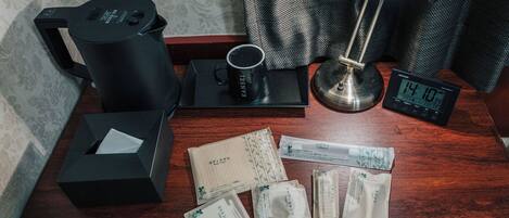 A wooden table with a coffee maker, a mug, a clock, and several tissue packets.