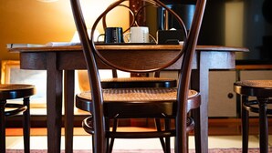 Zona pranzo con tavolo in legno, due sedie e un elemento decorativo a parete.
