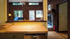 Une cuisine dotée d’un plan de travail en bois, d’un lave-vaisselle et d’une cheminée en pierre.