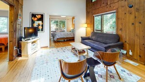 Un salon confortable avec un canapé, des fauteuils, un téléviseur et un mur en bois.