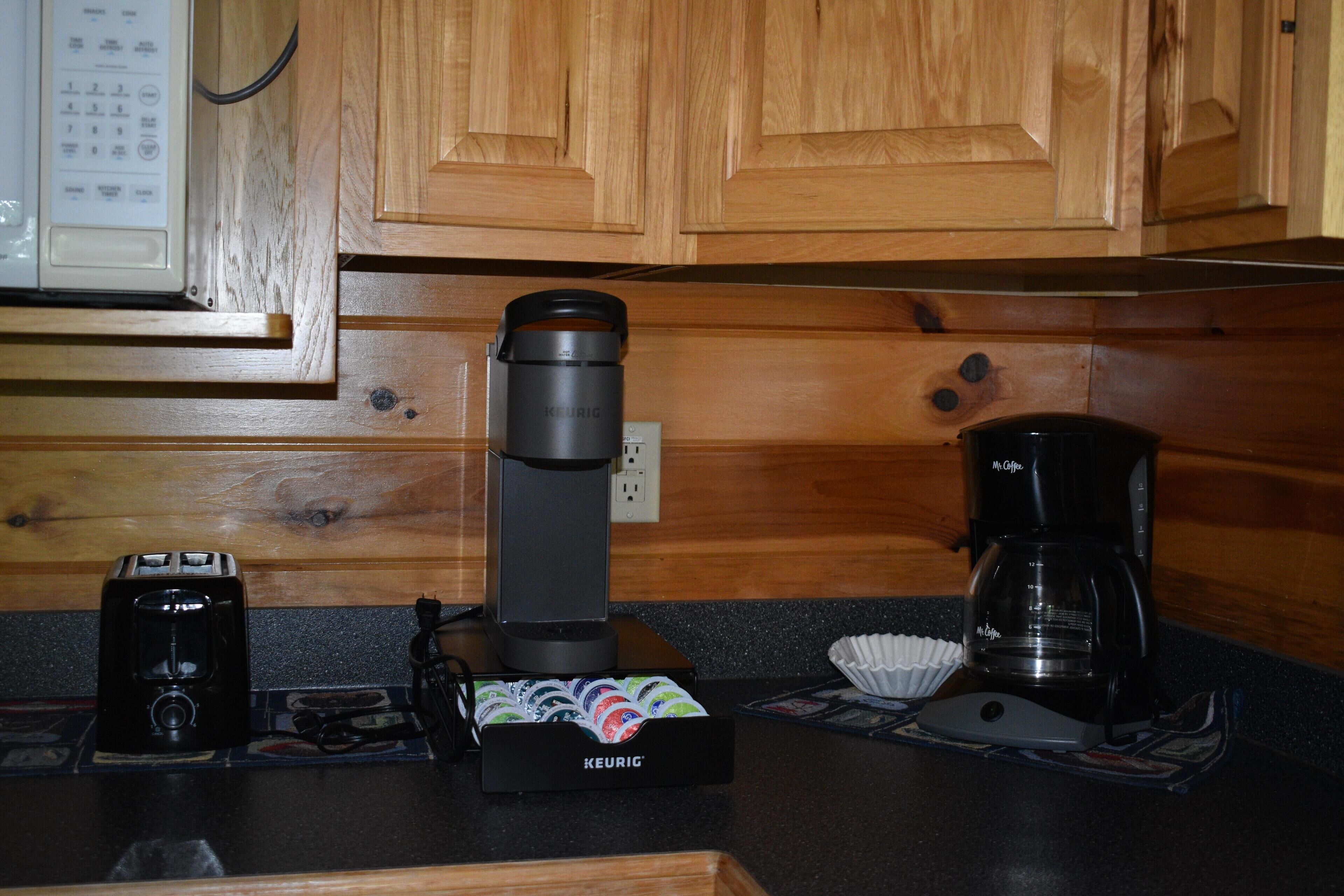 Une cuisine équipée de meubles en bois, d’une machine à café, d’un distributeur de capsules de café Keurig et d’un four à micro-ondes.